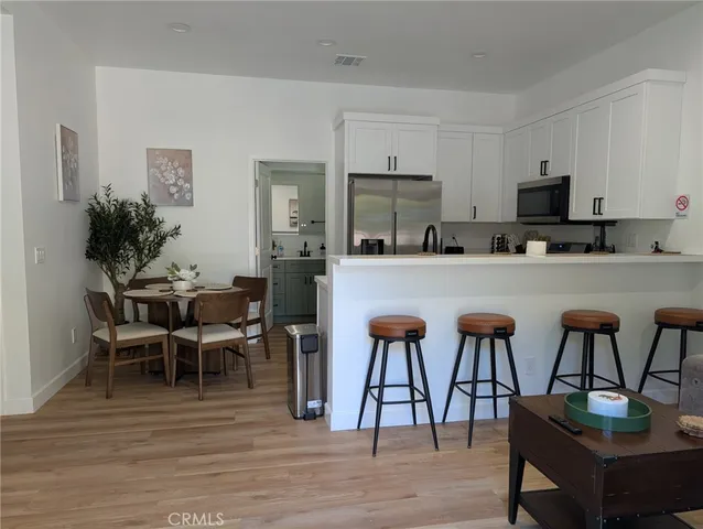 a kitchen with stainless steel appliances kitchen island granite countertop a table chairs and a refrigerator