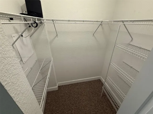 a view of a refrigerator in kitchen and an empty room
