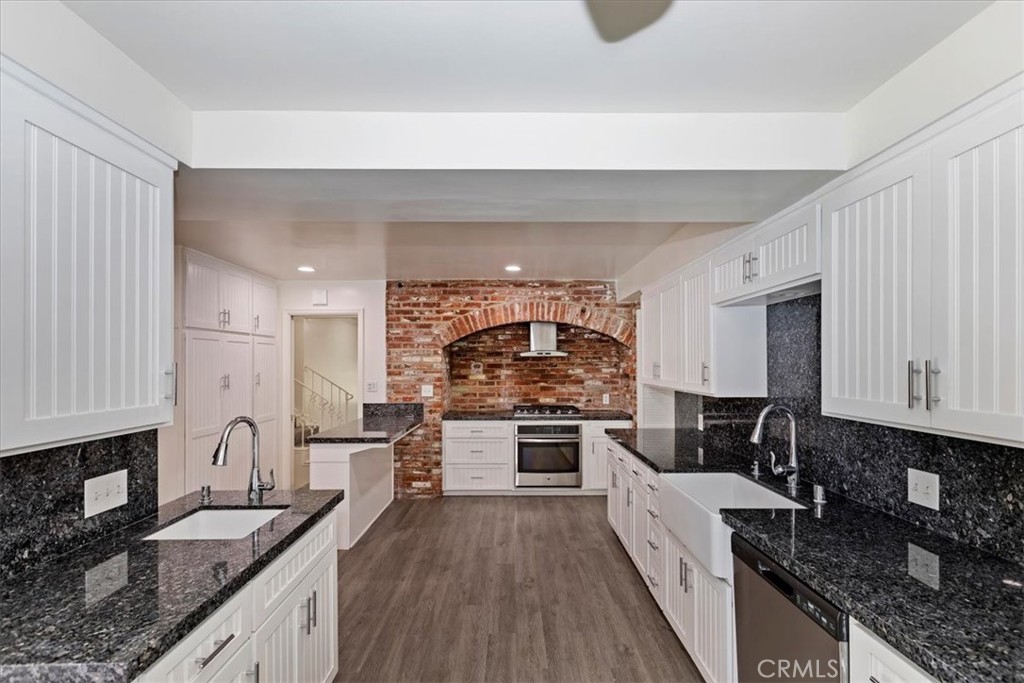 2154 Gainsborough Drive Riverside, CA 92506 - Photo 20 of 43 a kitchen with granite countertop a stove top oven a sink dishwasher and white cabinets with wooden floor