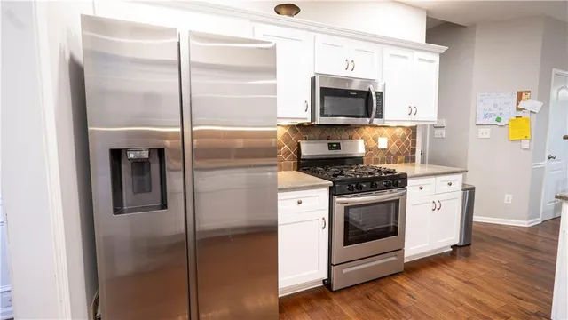 a kitchen with stainless steel appliances wooden floor sink and a microwave