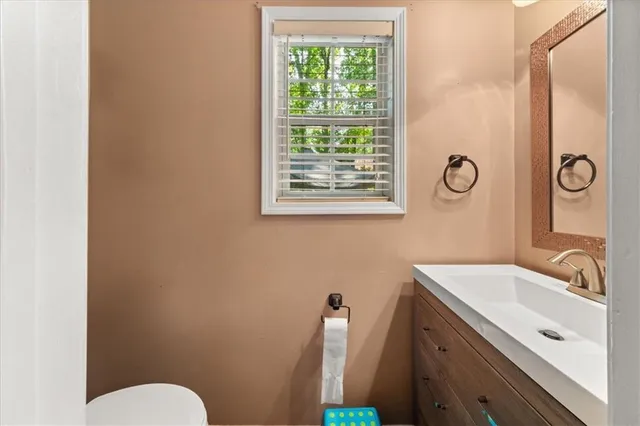 a bathroom with a sink a toilet a mirror and a window