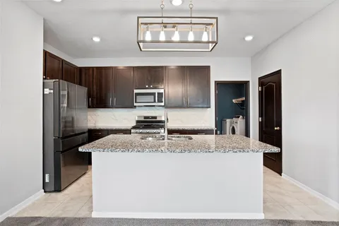 a kitchen with stainless steel appliances granite countertop a refrigerator a stove a sink a microwave and island