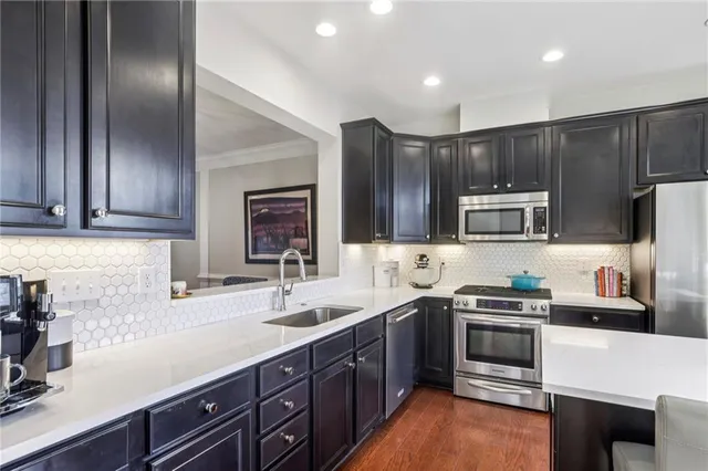 a kitchen with stainless steel appliances a sink a stove a microwave a refrigerator a sink and cabinets