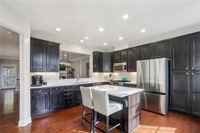 a kitchen with stainless steel appliances a sink a stove a refrigerator and island with wooden floor