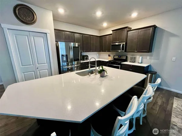 a large white kitchen with a sink a refrigerator and chairs