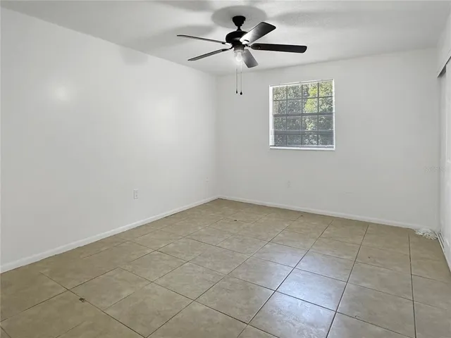 an empty room with a ceiling fan and a window