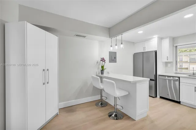 a kitchen with stainless steel appliances kitchen island granite countertop a sink and a refrigerator
