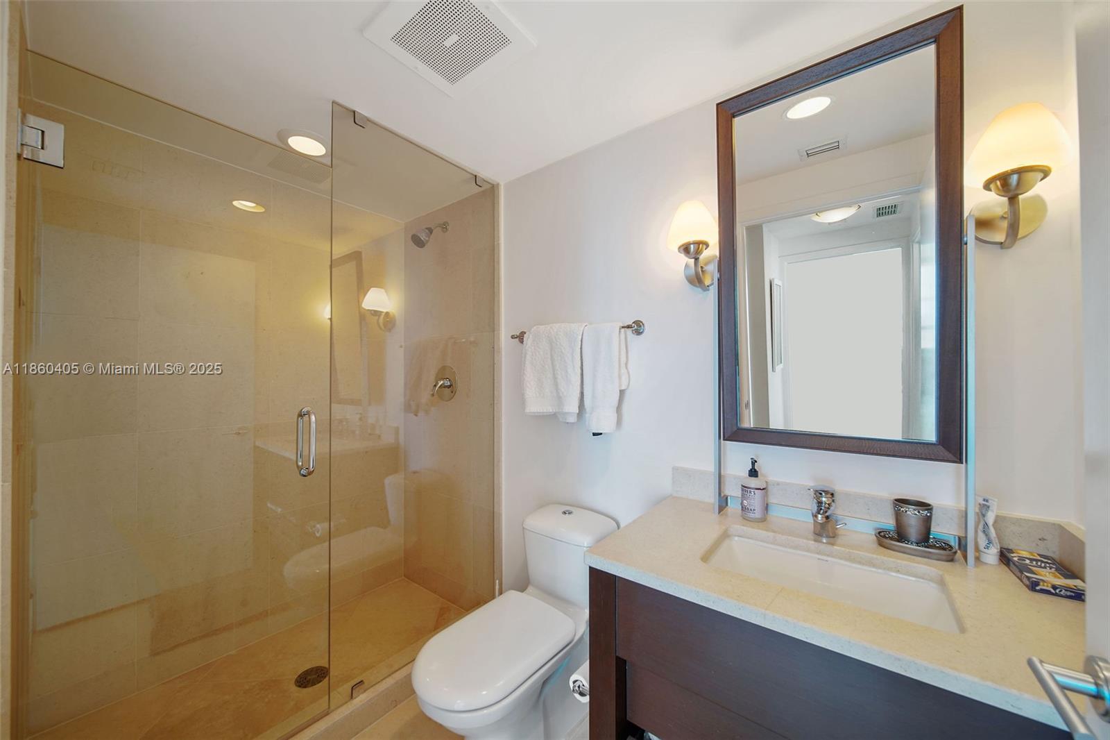 6899 Collins Avenue, Unit 1905 Miami Beach, FL 33141 - Photo 10 of 29 a bathroom with a granite countertop sink toilet a mirror a vanity and shower
