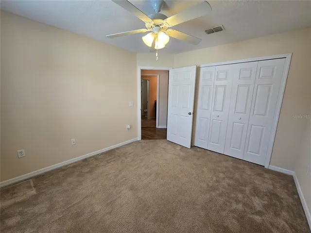 an empty room with closet and a ceiling fan