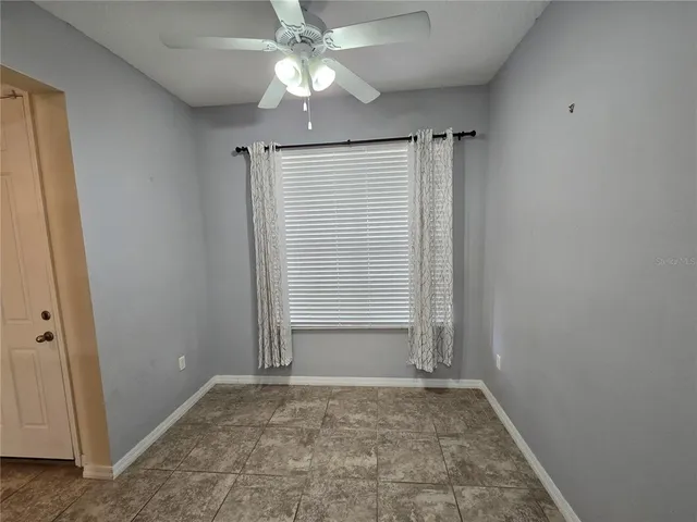 an empty room with a ceiling fan and carpet