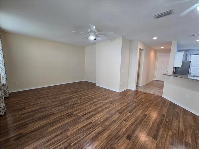 a view of empty room with wooden floor and fan