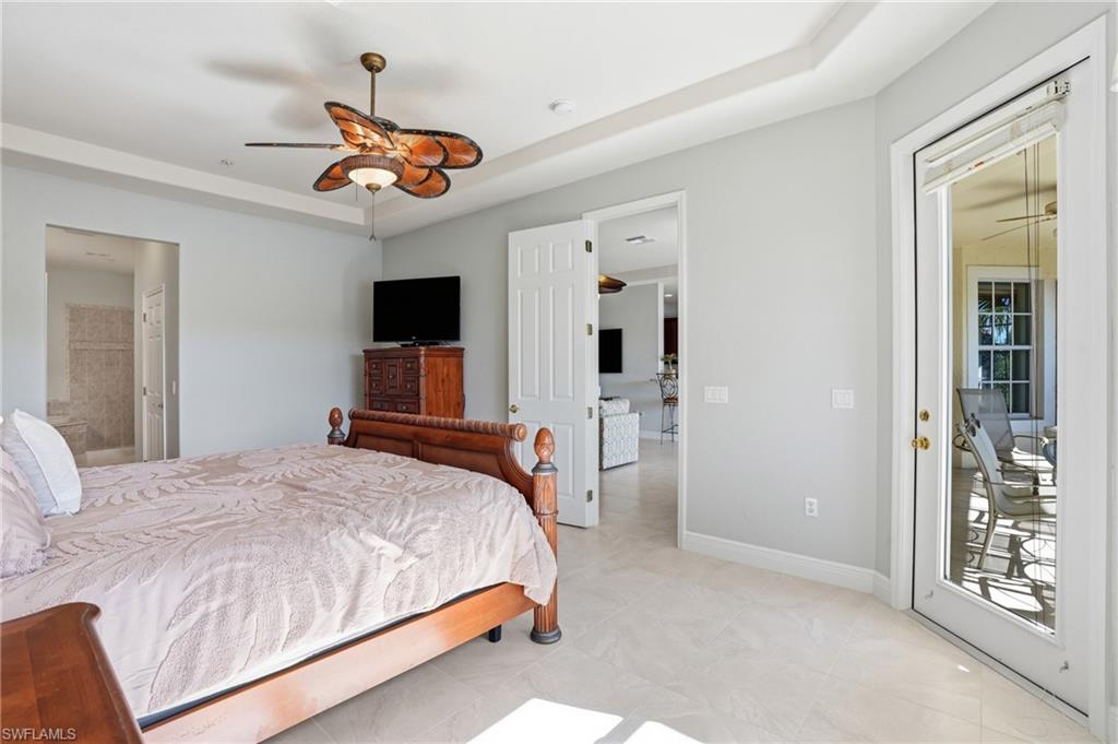 4620 Winged Foot Court, Unit 201 Naples, FL 34112 - Photo 22 of 44 Bedroom featuring a ceiling fan, connected bathroom, access to outside, and a tray ceiling