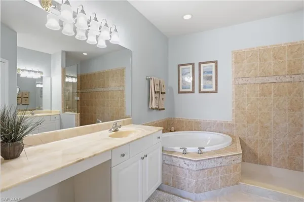 a bathroom with a tub a sink and mirror