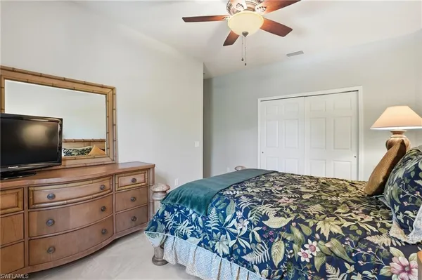 a bedroom with a bed and a flat tv screen on dresser