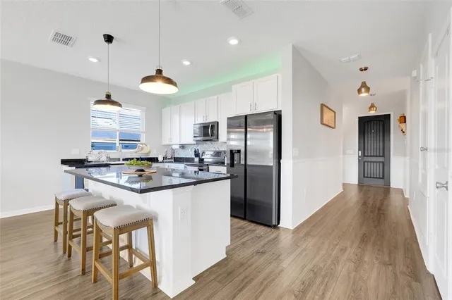 a kitchen with granite countertop a stove a refrigerator and a dining table with wooden floor