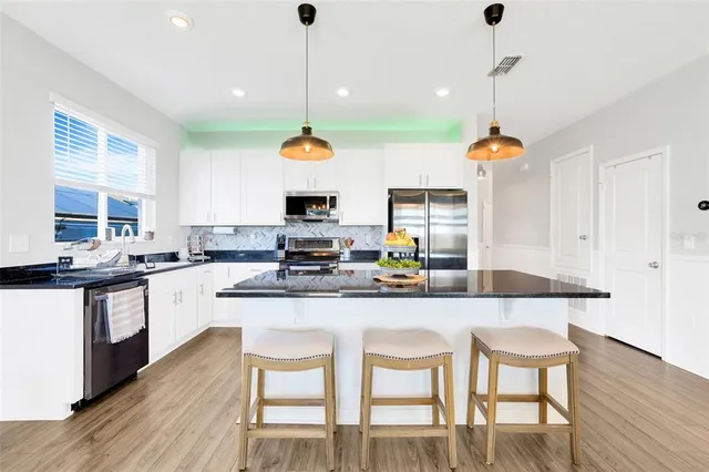 a kitchen with kitchen island granite countertop a sink a stove and a wooden floor