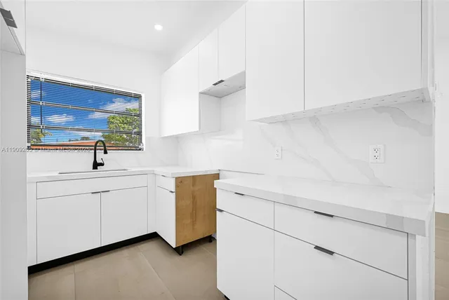 a kitchen with white cabinets and sink