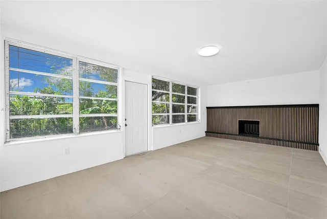 an empty room with a fireplace and large windows