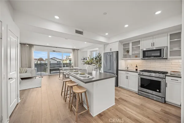 a kitchen with stainless steel appliances granite countertop a stove top oven a sink dishwasher a dining table and chairs with wooden floor