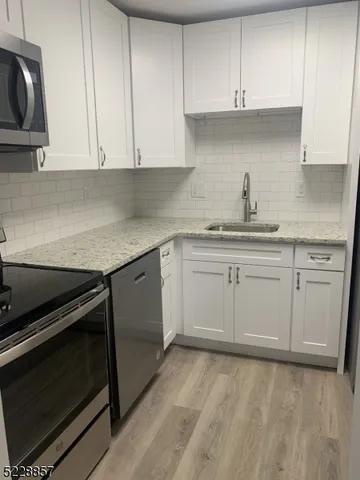 a kitchen with white cabinets stainless steel appliances and sink
