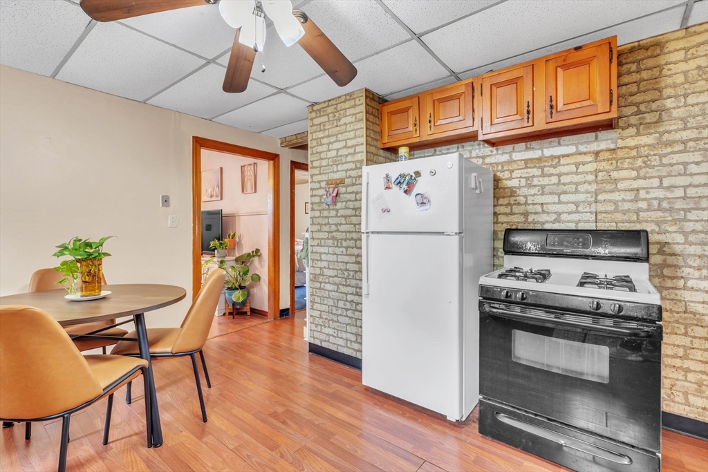 18 Goodwin Street Springfield, MA 01151 - Photo 7 of 31 a kitchen with stainless steel appliances a stove a refrigerator a dining table and chairs with wooden floor