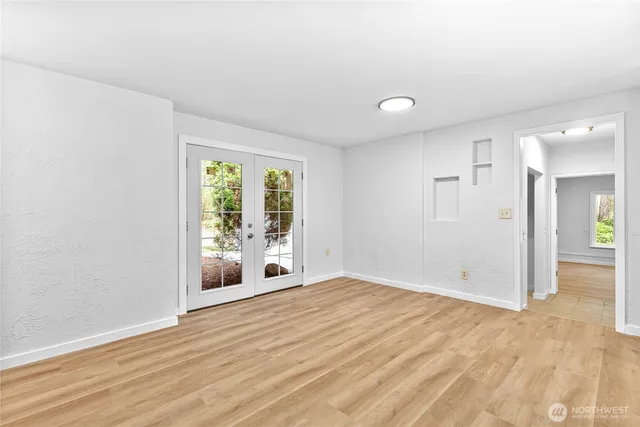 a view of an empty room with wooden floor and a window