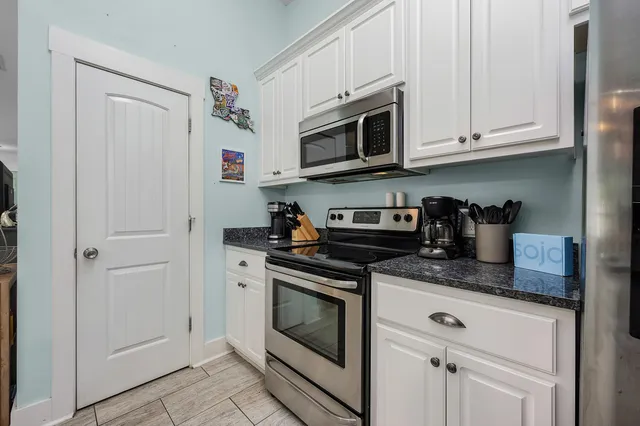 a kitchen with stainless steel appliances granite countertop white cabinets a stove a microwave and a sink