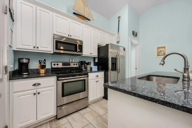 a kitchen with granite countertop a sink stainless steel appliances and white cabinets