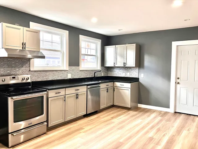 a kitchen with granite countertop a stove a sink and a microwave