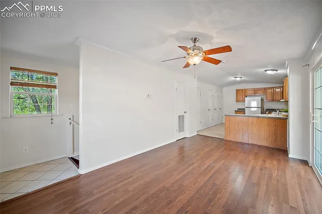 an empty room with wooden floor and a kitchen space with wooden floor