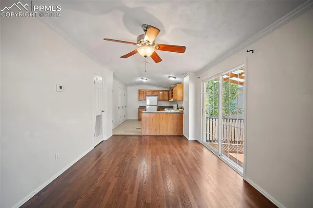 a view of a kitchen with wooden floor a ceiling fan and windows