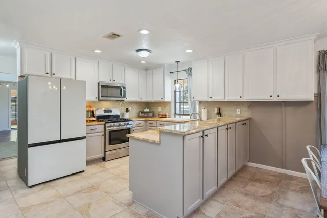 a kitchen with stainless steel appliances granite countertop a sink stove top oven and cabinets