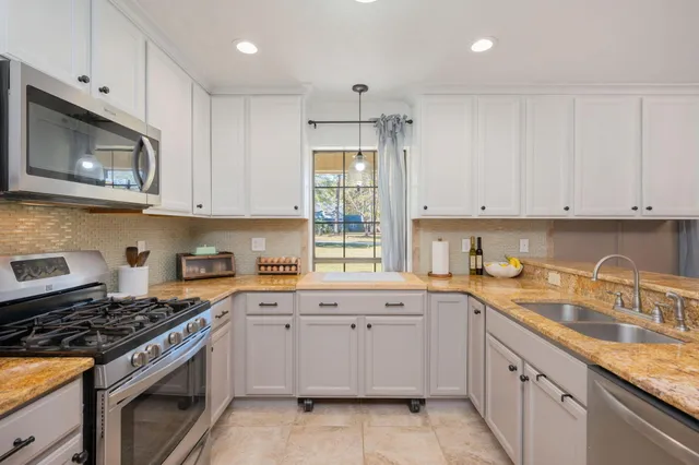 a kitchen with granite countertop white cabinets white stainless steel appliances and a sink