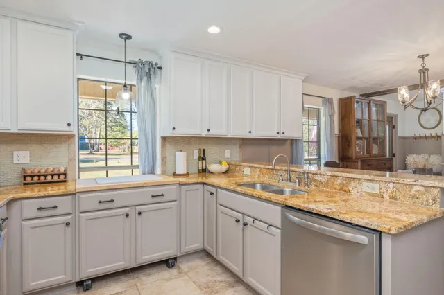 a kitchen with granite countertop a sink a stove and cabinets