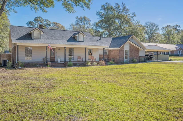 a front view of house with yard and trees in the background
