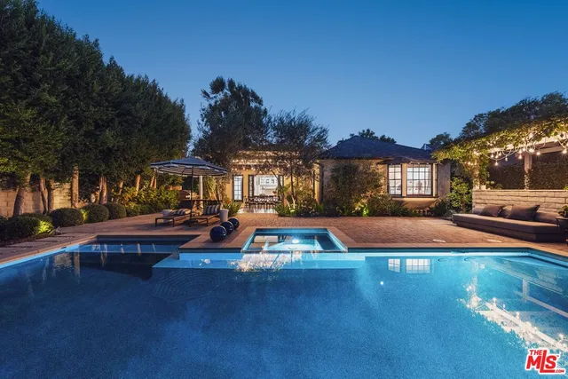a view of a swimming pool with lawn chairs under an umbrella
