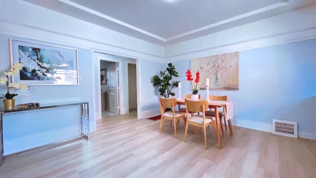 a dining room with furniture wooden floor a painting and a potted plant