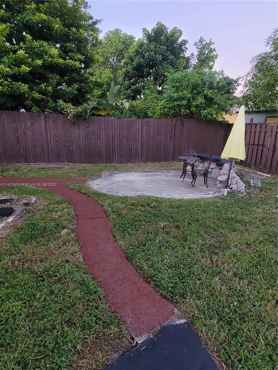 22780 Family Circle Boca Raton, FL 33428 - Photo 6 of 19 a view of a backyard with table and chairs with wooden fence