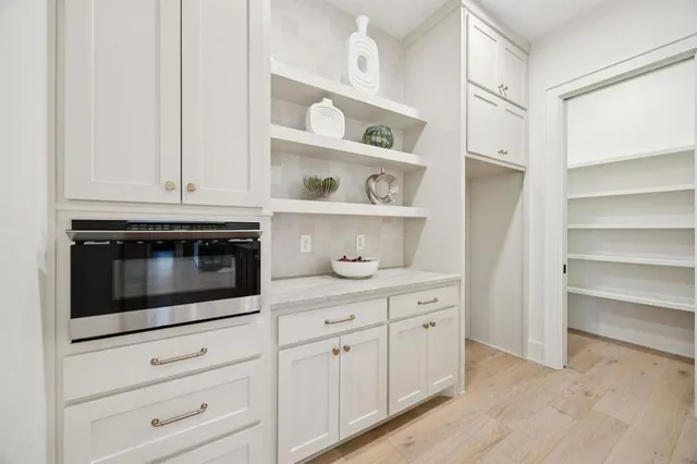 a kitchen with white cabinets and a stove with wooden floor