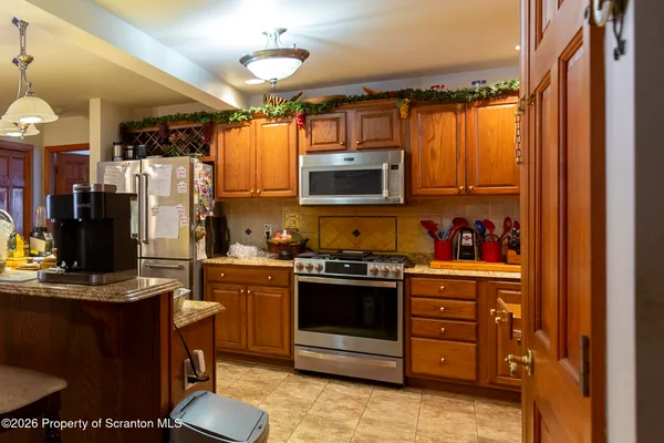 a kitchen with stainless steel appliances granite countertop a stove top oven a sink and a refrigerator