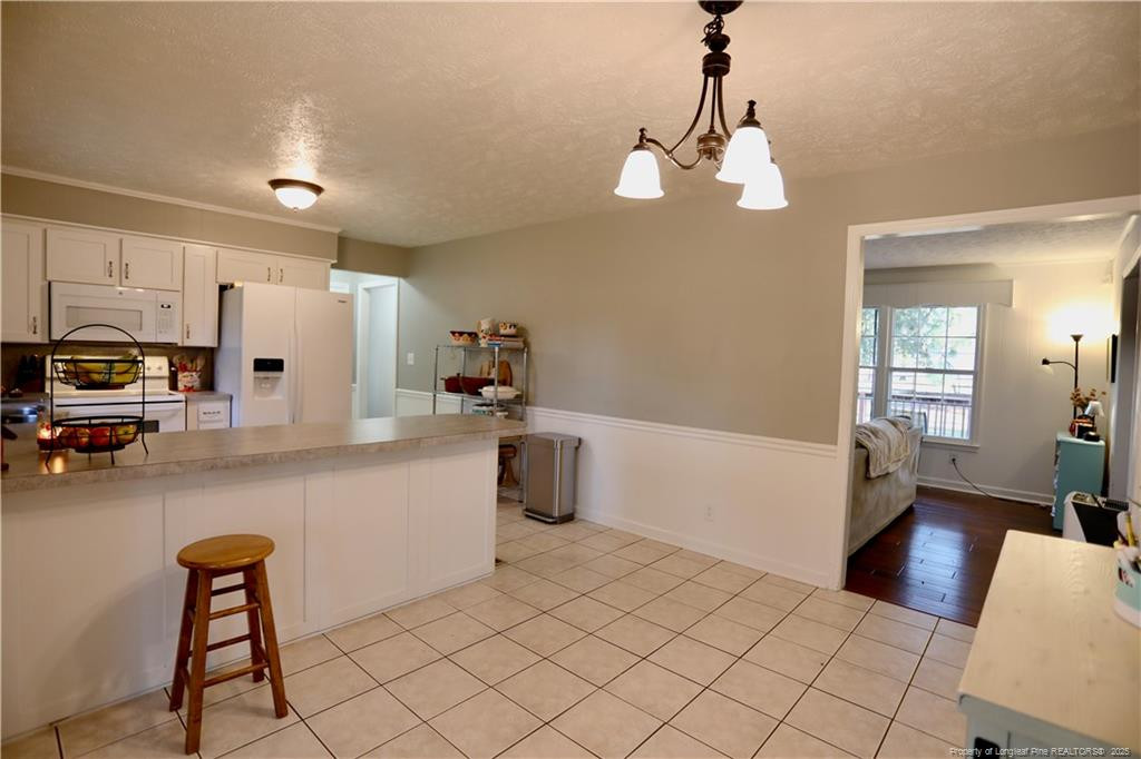 948 Pinebluff Lake Road Aberdeen, NC 28315 - Photo 12 of 32 a kitchen with a refrigerator a stove top oven a sink dishwasher and a dining table with wooden floor