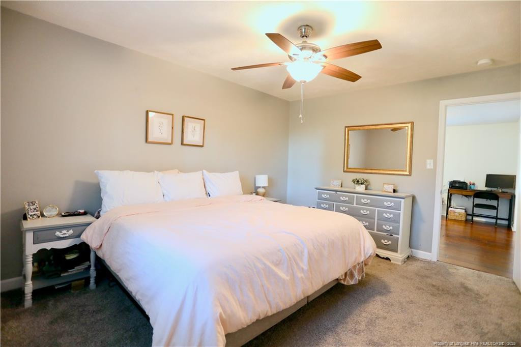 948 Pinebluff Lake Road Aberdeen, NC 28315 - Photo 19 of 32 a bedroom with a large bed a chandelier and a flat tv screen on dresser