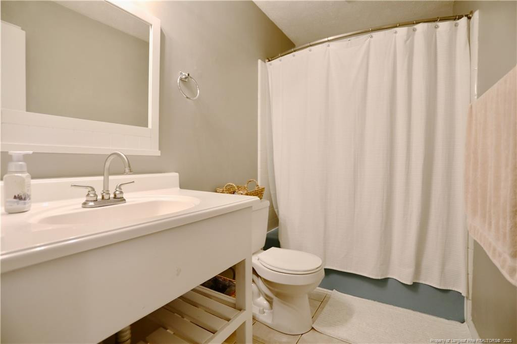 948 Pinebluff Lake Road Aberdeen, NC 28315 - Photo 21 of 32 a bathroom with a sink a toilet and shower curtain