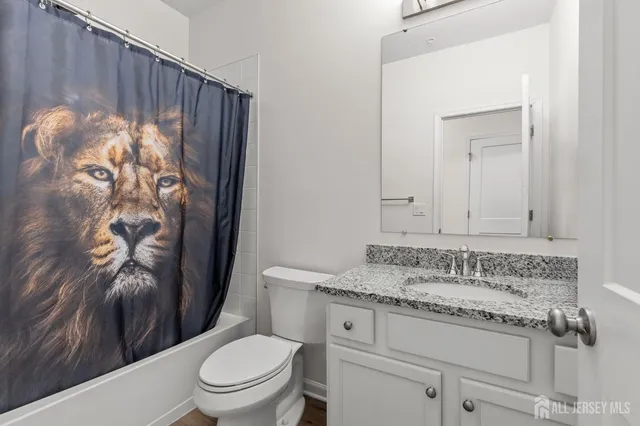 a bathroom with a granite countertop sink a toilet and a shower curtain