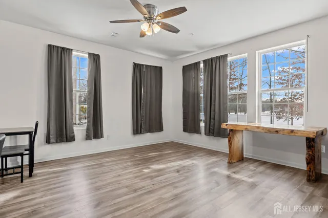 a view of an empty room with window and wooden floor