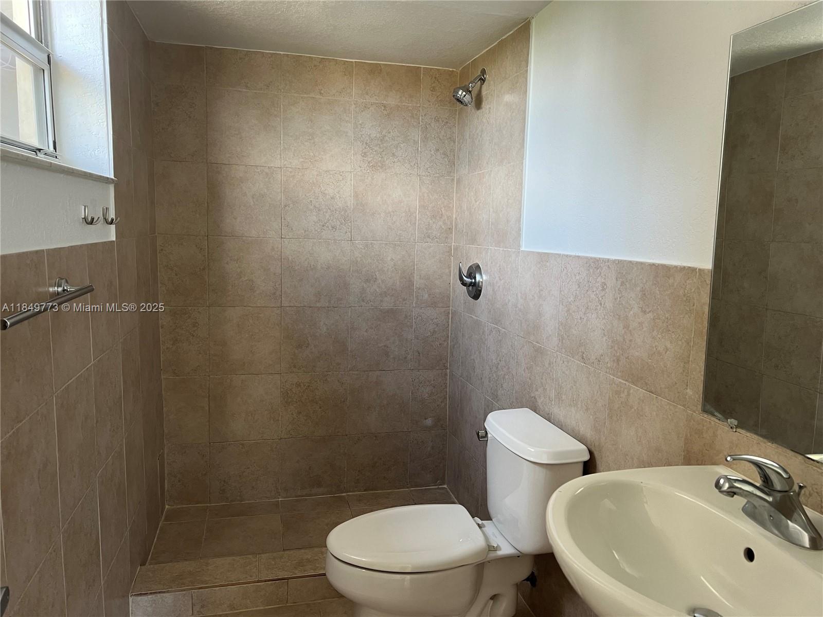 8950 Southwest 69th Court, Unit 312 Pinecrest, FL 33156 - Photo 11 of 13 a bathroom with a sink a toilet and a shower
