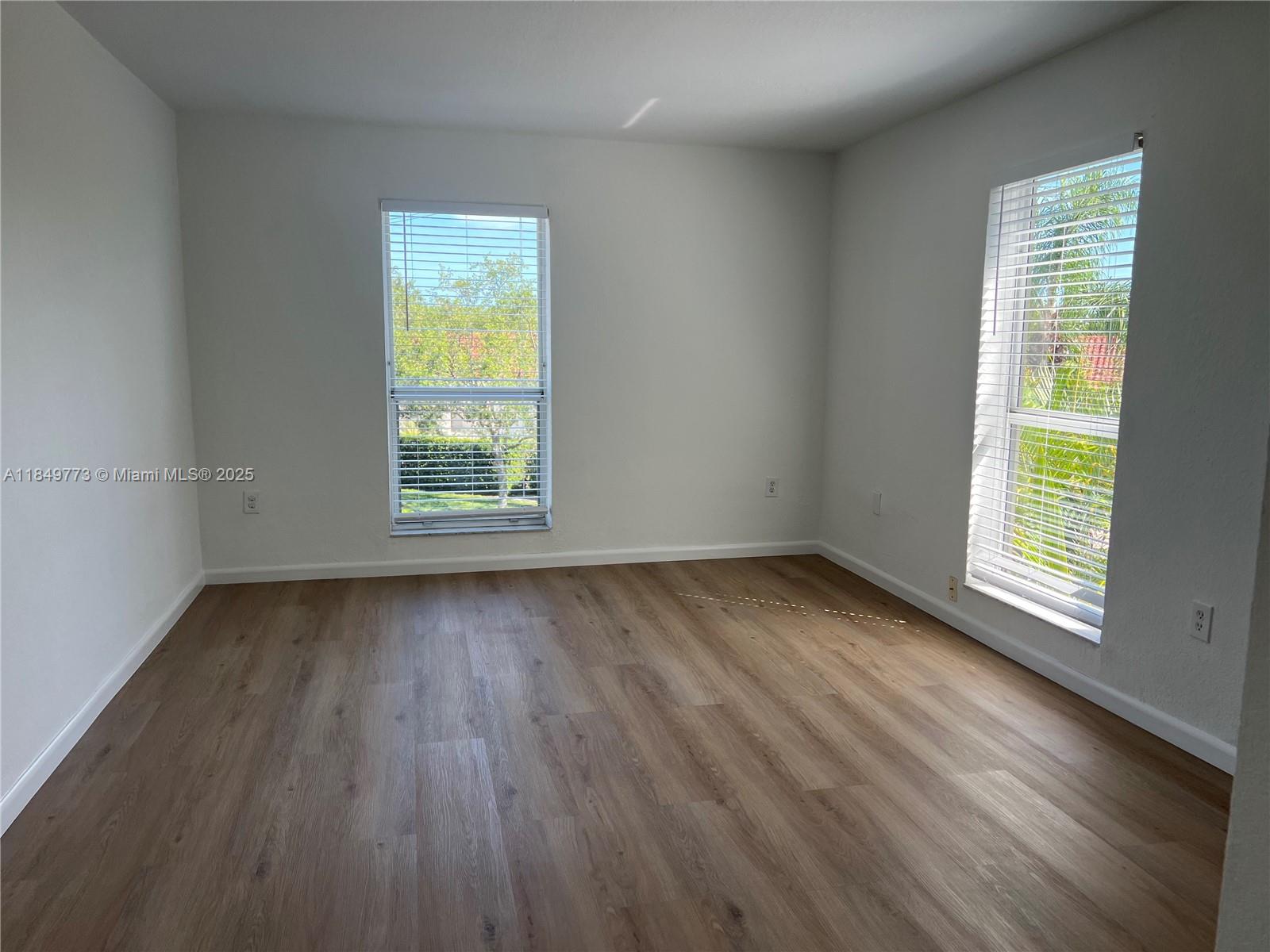 8950 Southwest 69th Court, Unit 312 Pinecrest, FL 33156 - Photo 9 of 13 an empty room with wooden floor and windows
