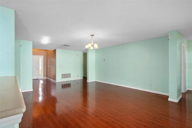 a view of an empty room with wooden floor and a chandelier
