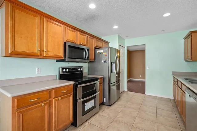 a kitchen with granite countertop a stove top oven microwave and refrigerator