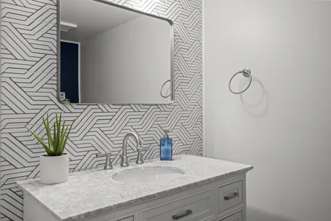 a bathroom with a granite countertop sink a mirror and shower